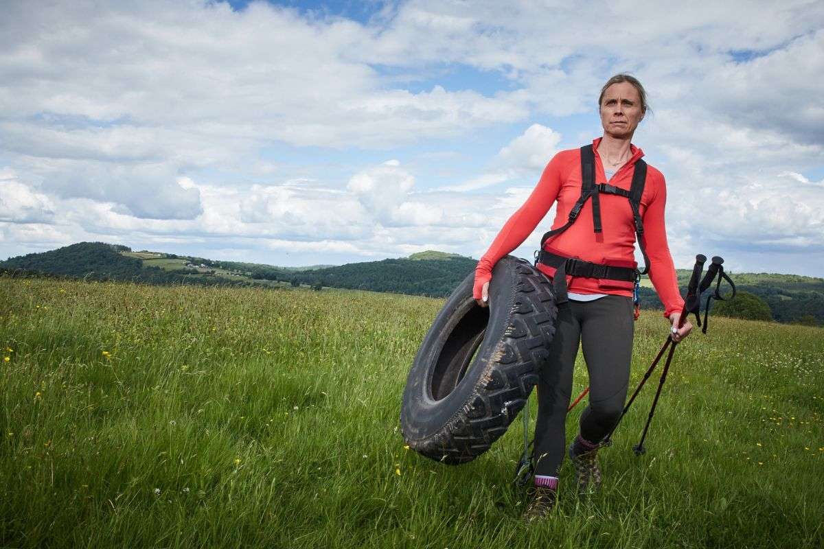 woman carrying big tire and while hiking